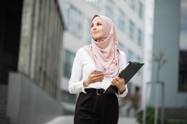 Ofis merkezinde cep telefonu olan Müslüman iş kadını.