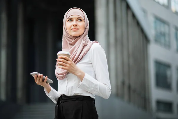 Arab nő kezében kávé és okostelefon az utcán — Stock Fotó