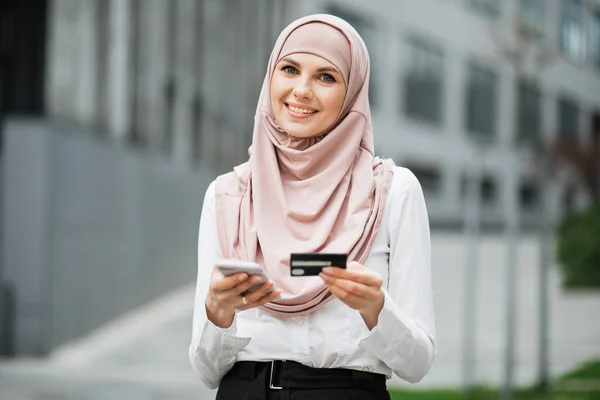 히잡을 하는 여자가 쇼핑을 위해 휴대 전화와 신용 카드를 사용하는 모습 — 스톡 사진