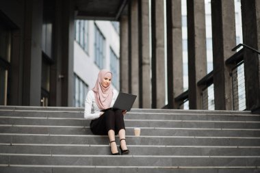 Ofis yakınında dizüstü bilgisayarda çalışan Müslüman bir kadın.