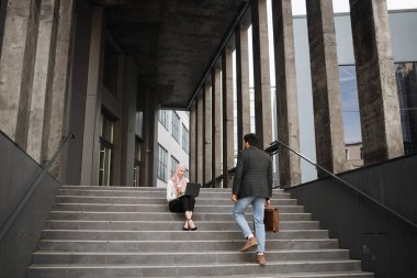 Laptoplu iki Müslüman dışarıda buluşuyor.