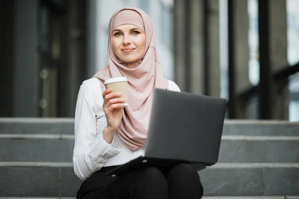 히잡에 있는 여자 가 바깥에서 노트북으로 일하고 있는 모습 — 스톡 사진