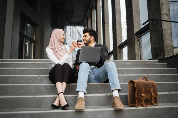 Muslimische Mitarbeiter stoßen mit Tassen Kaffee im Freien an — Stockfoto