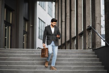 Arablı adam merdivenlerde duruyor cep telefonu ve bavuluyla