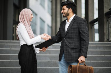 Hindu adam ve kadın tesettürde el sıkışıyor.