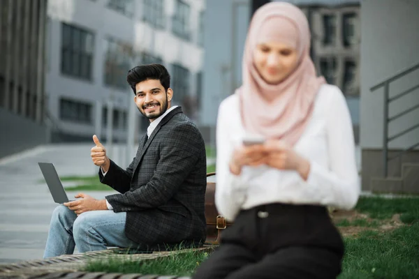 Аравійські комерсанти користуються ноутбуком і мобільним телефоном на вулиці. — стокове фото