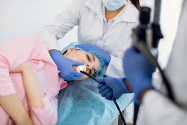 Genç bayan hasta modern klinikte kanepede yatıyor, gastroskopik muayene oluyor.