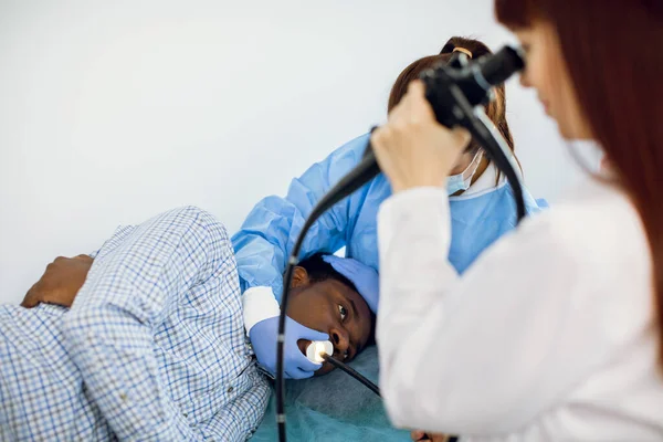 Jovem afro-americano homem paciente deitado no sofá no hospital, durante o procedimento de endoscopia — Fotografia de Stock