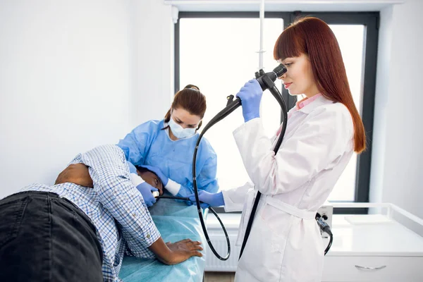Médico gastroenterologista concentrado feminino, operando endoscópio durante procedimento gastroscópico — Fotografia de Stock