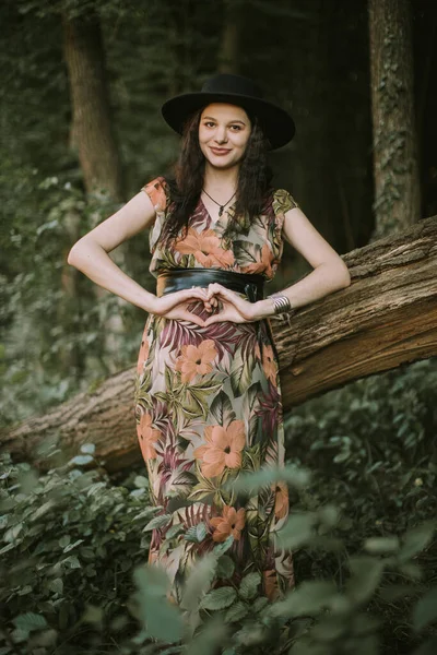 Mujer embarazada mostrando las manos en forma de corazón al aire libre en el bosque de verano —  Fotos de Stock