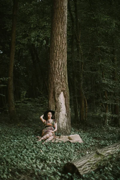 Portrait d'une jeune femme enceinte jouissant de la forêt avec des émotions de rêve, assise sous l'arbre — Photo