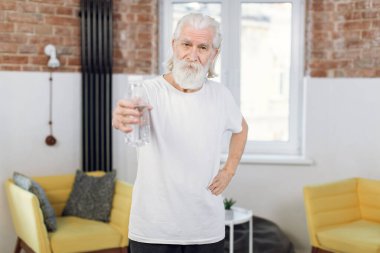 Yaşlı adam idmandan sonra elinde bir şişe su tutuyor.