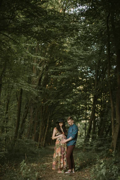 Superbe jeune femme enceinte et bel homme joyeux, marchant ensemble dans une belle forêt — Photo