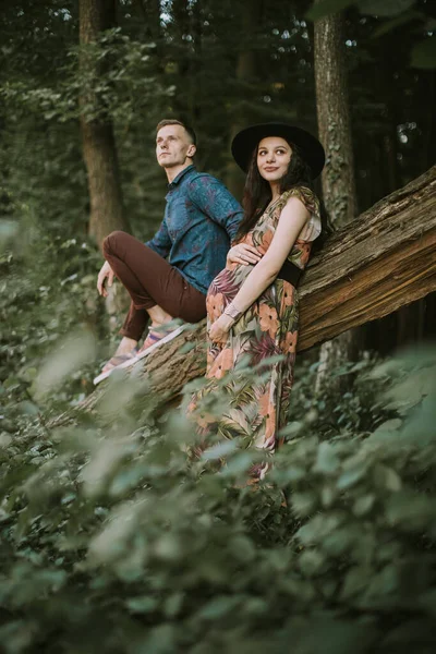 Schwangere Mädchen mit großem süßen Bauch und junger Mann im schönen Wald — Stockfoto