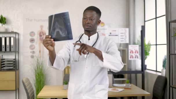 Médico afro-americano do sexo masculino olhando para os pacientes raio-x na clínica médica — Vídeo de Stock
