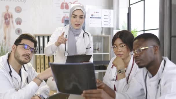 Multietniska läkare som analyserar röntgenundersökning av patientlungor — Stockvideo