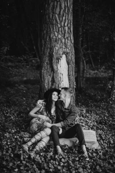 Έγκυος γυναίκα με τον άντρα της, περπατούσε στο δάσος, καθόταν κάτω από το δέντρο και χαμογελούσε ο ένας στον άλλο — Φωτογραφία Αρχείου