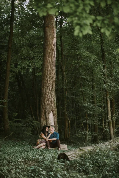Homme et femme, se promenant dans la forêt, assis sous le grand arbre, embrassant et embrassant — Photo