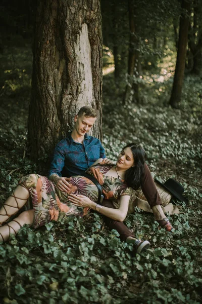 Glückliche Familie, schwangere Frau und gutaussehender Mann, die sich bei einem Spaziergang im schönen Sommerwald ausruhen — Stockfoto