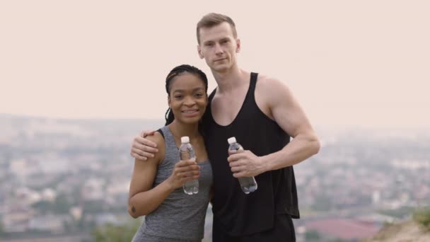 Cuplu pozitiv în îmbrăcăminte sport cu sticlă de apă în aer liber — Videoclip de stoc