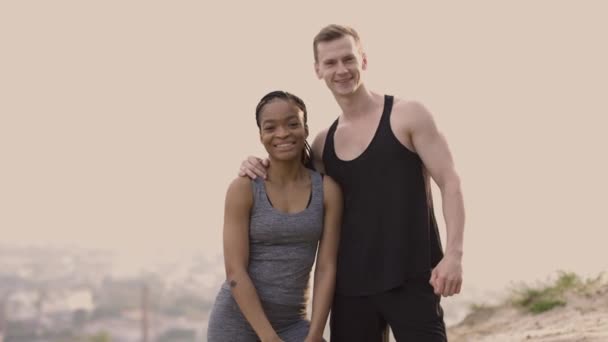 Primer plano de feliz pareja multirracial mostrando sus fuertes bíceps, posando al aire libre — Vídeos de Stock