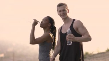 Genç çift spor sonrası içme suyu içiyor.