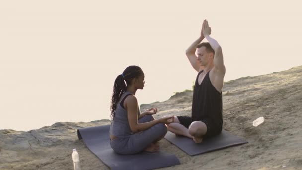 Multikulturellt par mediterar med slutna ögon utomhus — Stockvideo