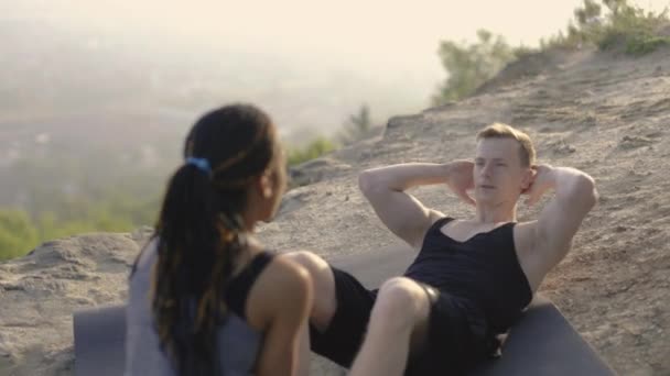 Kaukasischer Athlet Mann macht Übungen für Bauch, während Frau seine Beine hält — Stockvideo