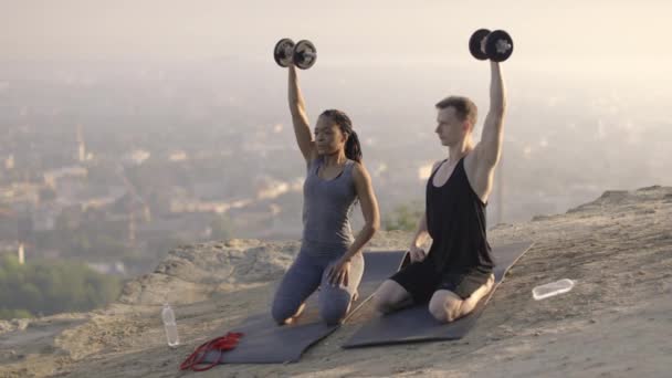 Vielrassiges Paar in Sportkleidung gibt High Five nach dem Training mit Hanteln — Stockvideo