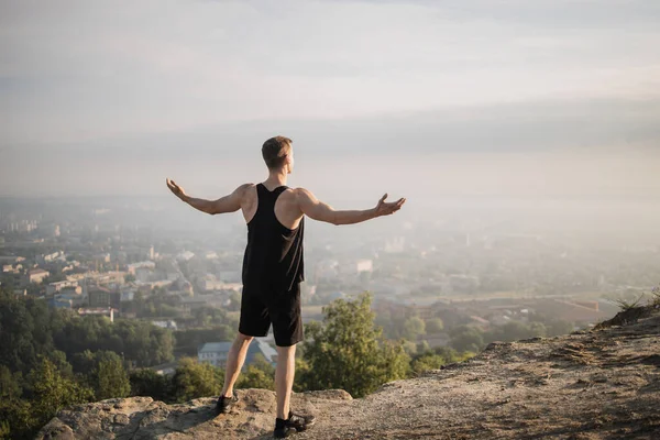 Yüksek tepede rahatlayan kaslı adamın arka görüntüsü