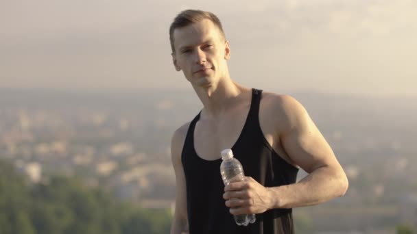 Männlicher Athlet hält Wasserflasche und Yogamatte im Freien und zeigt Daumen hoch — Stockvideo