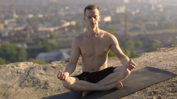 Расслабленный мужчина без рубашки практикует йогу на свежем воздухе, медитирует — стоковое видео