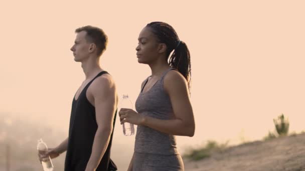 スポーツ後のアフリカの女性と白人男性飲料水 — ストック動画