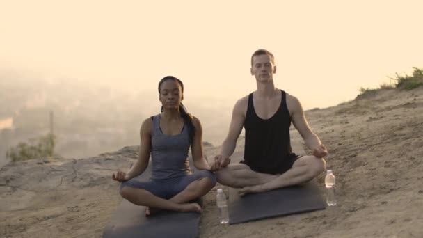 Multicultureel paar meditatie op yoga mat buiten — Stockvideo