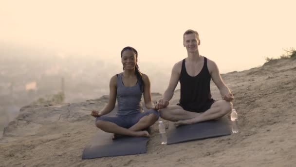 Multiculturális pár meditáció jóga szőnyegen a szabadban — Stock videók