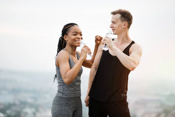 Casal multiétnico provável em sportswear com garrafa de água ao ar livre — Fotografia de Stock