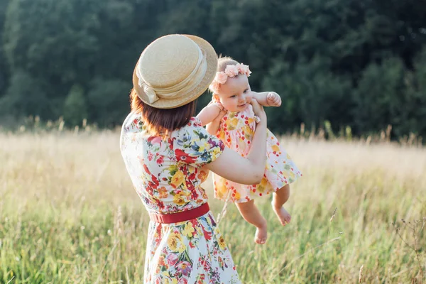 Mãe e linda filhinha brincando no campo, circulando com bebê no campo. — Fotografia de Stock