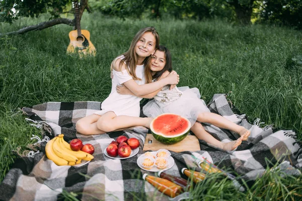 Duas irmãs bonitos abraçando ao ar livre durante o piquenique — Fotografia de Stock