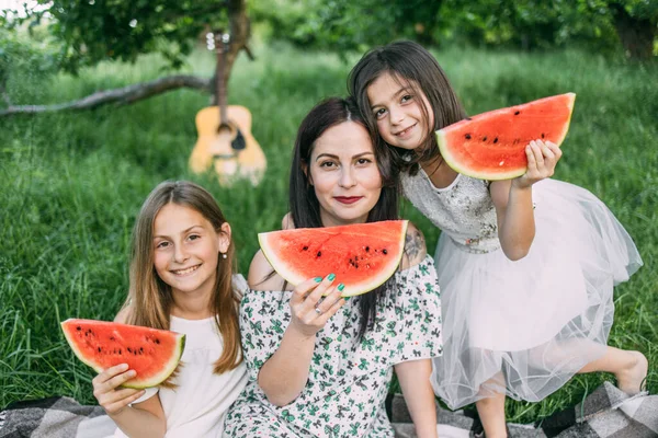Mulher com duas filhas melancia doce em piquenique — Fotografia de Stock