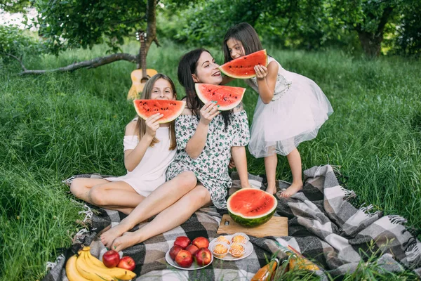 Mulher com duas filhas melancia doce em piquenique — Fotografia de Stock