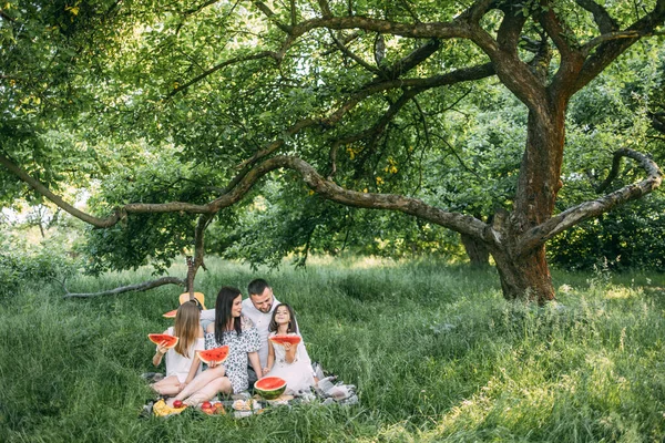 Jeunes parents avec deux filles mangeant de la pastèque sur pique-nique — Photo