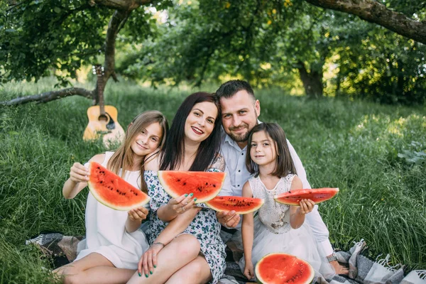 Bahçede ellerinde karpuzla oturan çocuklu bir çift. — Stok fotoğraf