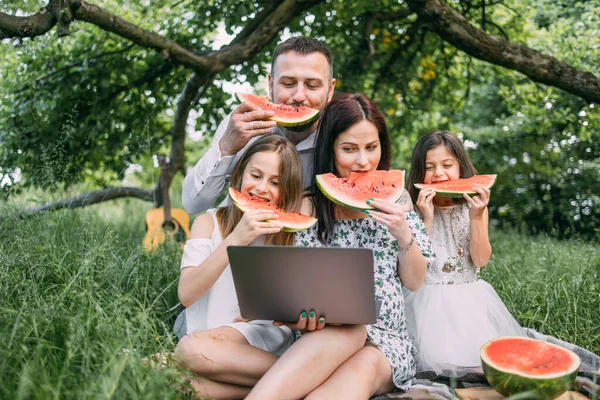 Positieve familie met moderne laptop genieten van picknick tijd — Stockfoto