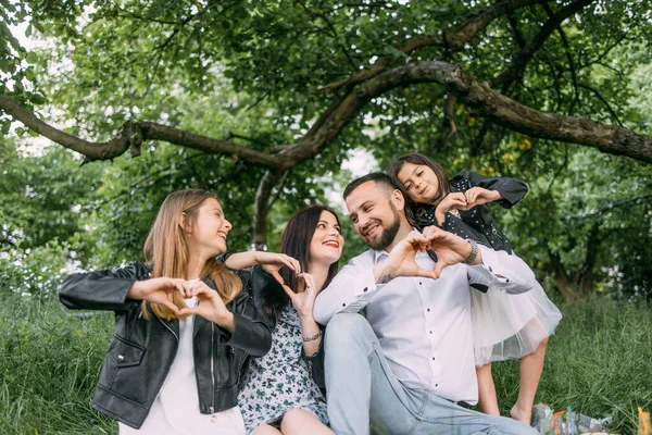 Famille heureuse de quatre montrant signe d'amour à l'extérieur — Photo