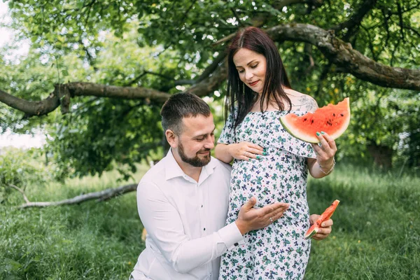 Красивий чоловік обіймає вагітну дружину на відкритому повітрі — стокове фото