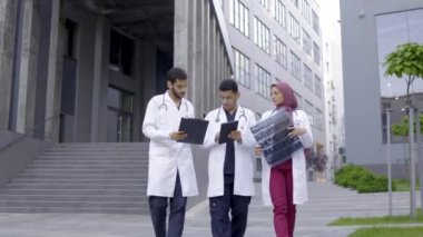 Üç doktor, tesettürlü bir kadın ve tıbbi giysili iki adam hastaların röntgen taramasını tartışıyorlar.