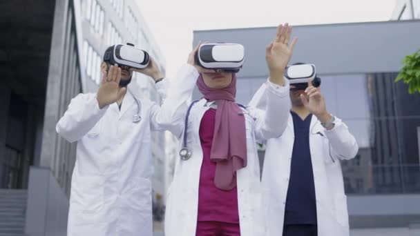 Equipo multirracial de tres médicos con gafas de realidad virtual que trabajan fuera del hospital — Vídeo de stock
