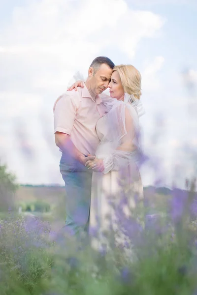 Feliz casal de meia-idade, abraçando e desfrutando de momentos românticos juntos no campo da lavanda — Fotografia de Stock