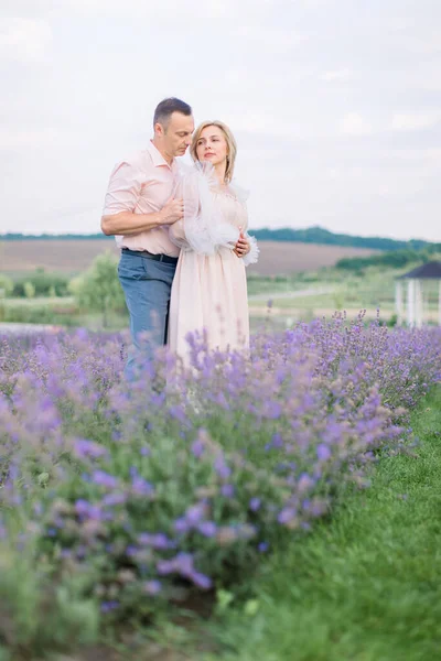 Glückliches romantisches reifes verliebtes Paar, das auf dem violetten Lavendelfeld steht und sich umarmt — Stockfoto