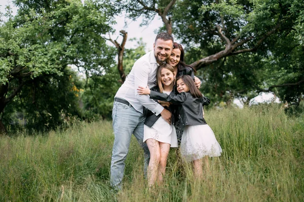 Família caucasiana de quatro abraços no jardim de verão verde — Fotografia de Stock